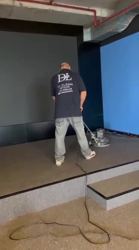 Técnico do Grupo DL Clean limpando o carpete de um auditório com palco