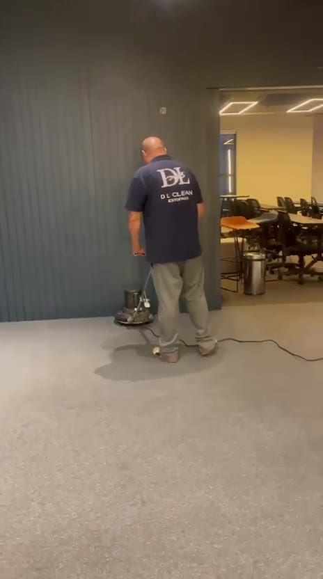 Técnico do Grupo DL Clean passando enceradeira rotativa no carpete de um escritório
