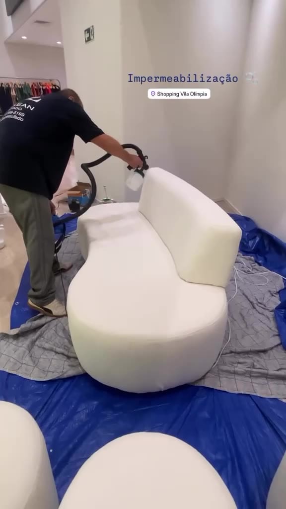 Técnico do Grupo DL Clean aplicando impermeabilizante em um sofá branco curvo