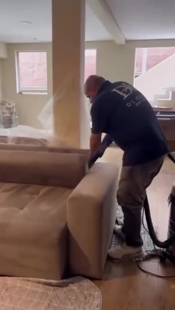 Técnico do Grupo DL Clean fazendo extração em um sofá bege de sala
